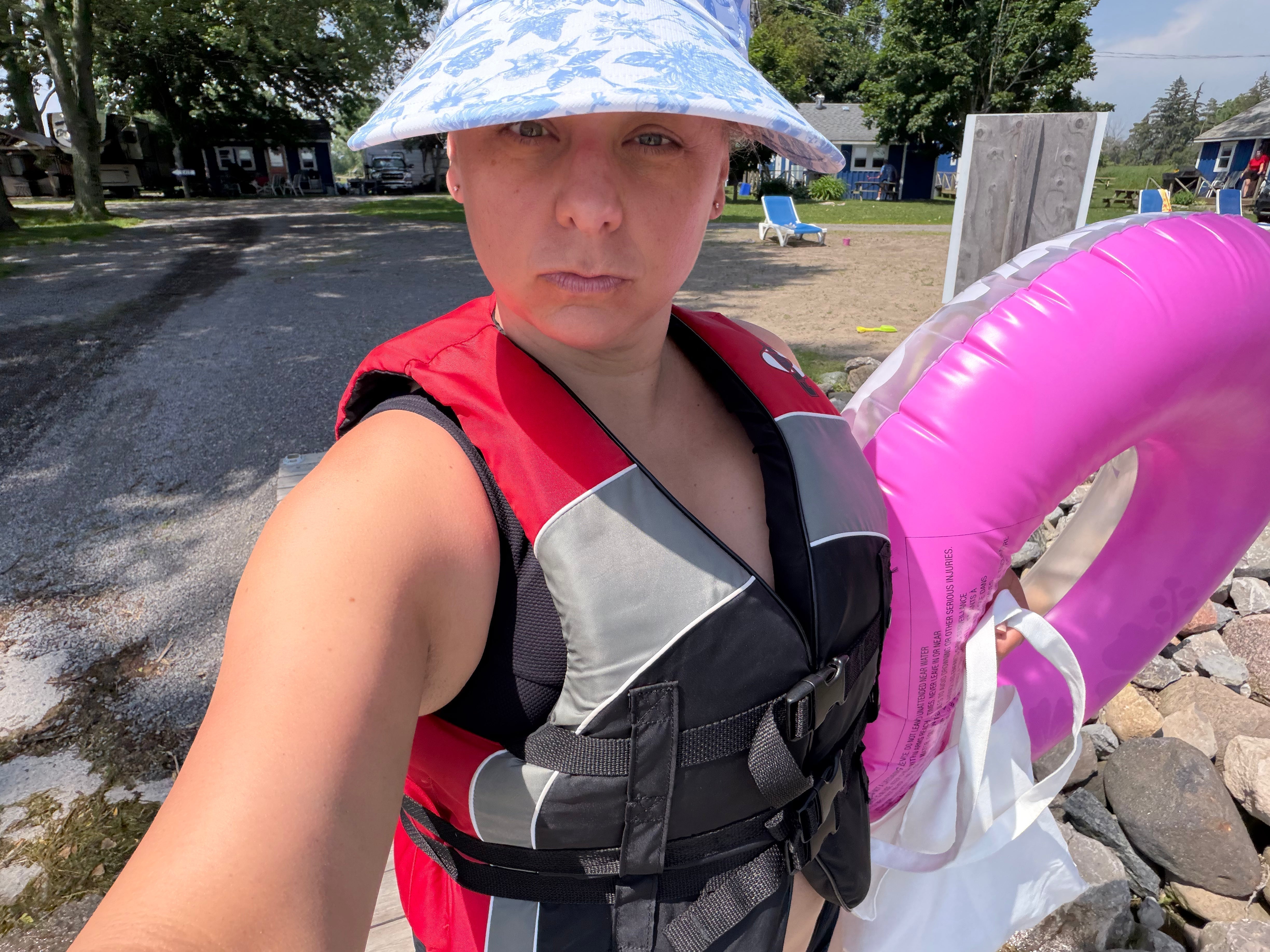 A woman wearing a summer hat with life jacket and a floaty for protection